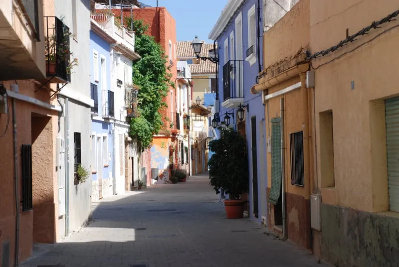 Bunte Häuserfassaden säumen eine schmale Gasse in der Altstadt von Dénia, Spanien.
